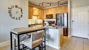A modern kitchen with wooden cabinets, stainless steel appliances, and a unique wall clock. - Easy E470 & 125 Access! Quiet Englewood Condo (Parker)