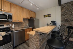 A kitchen with wooden cabinets, a stone island, stainless steel appliances, and a sign indicating a 'Jabber Wocky' direction.