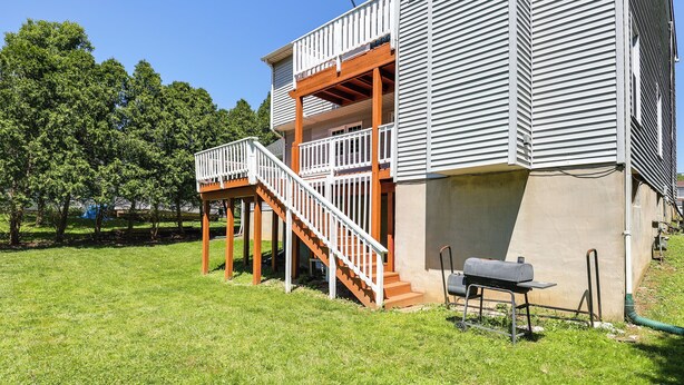 Una casa de dos pisos con un porche de madera y una escalera que lleva a un balcón.