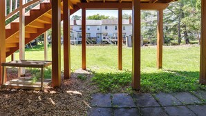 Un espacio al aire libre cubierto con una escalera de madera, una mesa pequeña y un sendero de piedra que lleva a un césped.