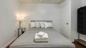 Un dormitorio con cama, lámpara de noche y una puerta.
