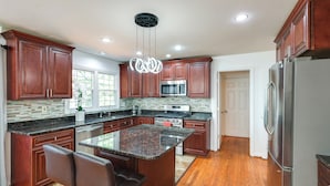 A kitchen with dark wood cabinets, a granite island, stainless steel appliances, and a bar stool. - 1 Mi to Main St! Family-friendly Reisterstown Home (Reisterstown)