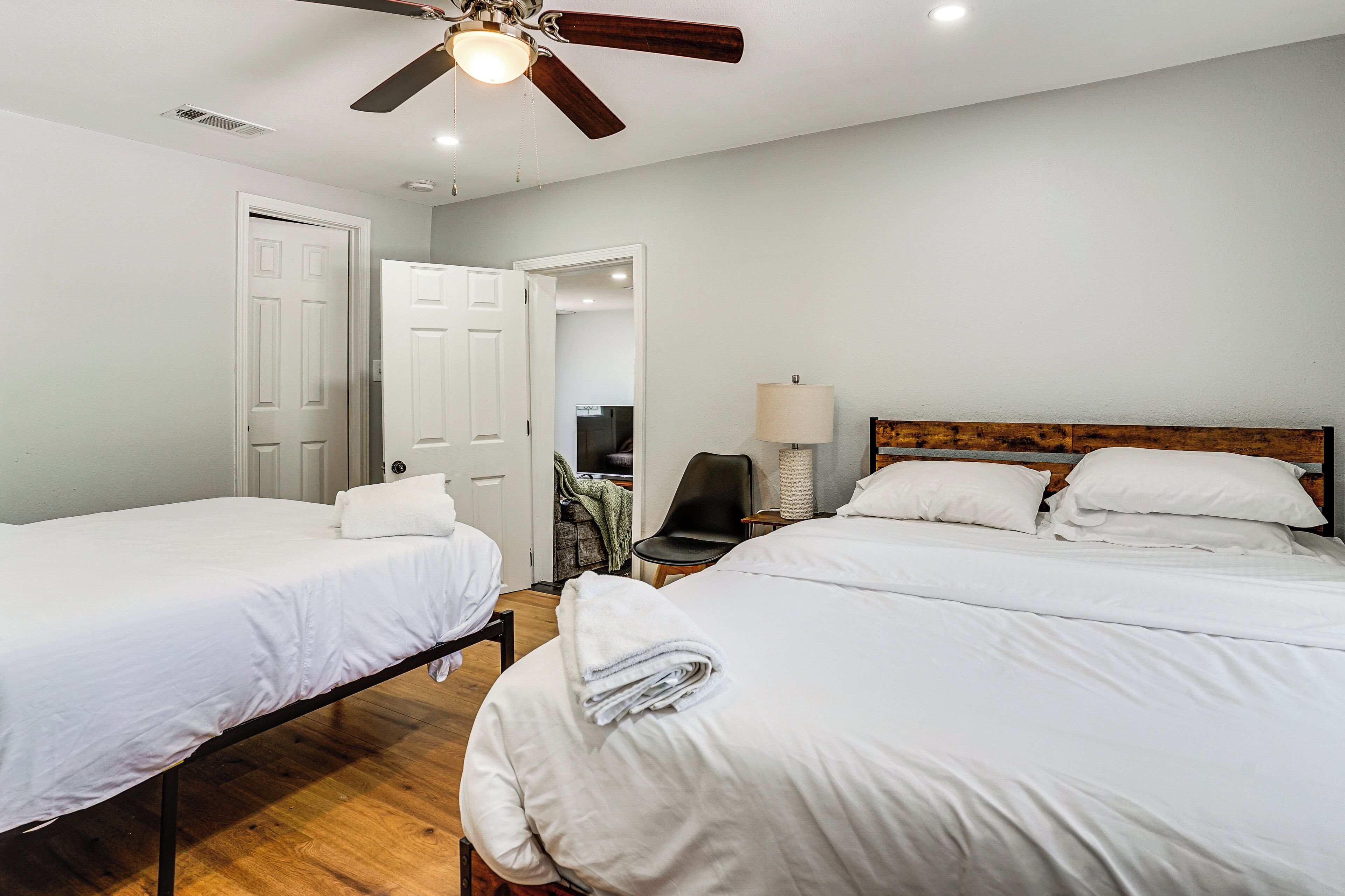 A hotel room with two single beds, a wooden headboard, a ceiling fan, and a lamp.