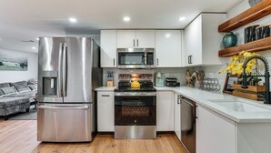 A modern kitchen with stainless steel appliances, white cabinetry, and a wooden floor. - Walk to Historic Weatherford: Home w/ Yard (Weatherford)