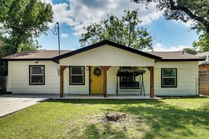 A single-story house with a front porch, a yellow door, and a small front yard. - Walk to Historic Weatherford: Home w/ Yard (Weatherford)