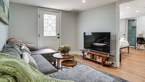 A living room with a sofa set, a television, a small table with a vase, and a door with a decorative glass panel.