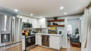 A modern kitchen with stainless steel appliances, white cabinetry, and a wooden floor. - Walk to Historic Weatherford: Home w/ Yard (Weatherford)