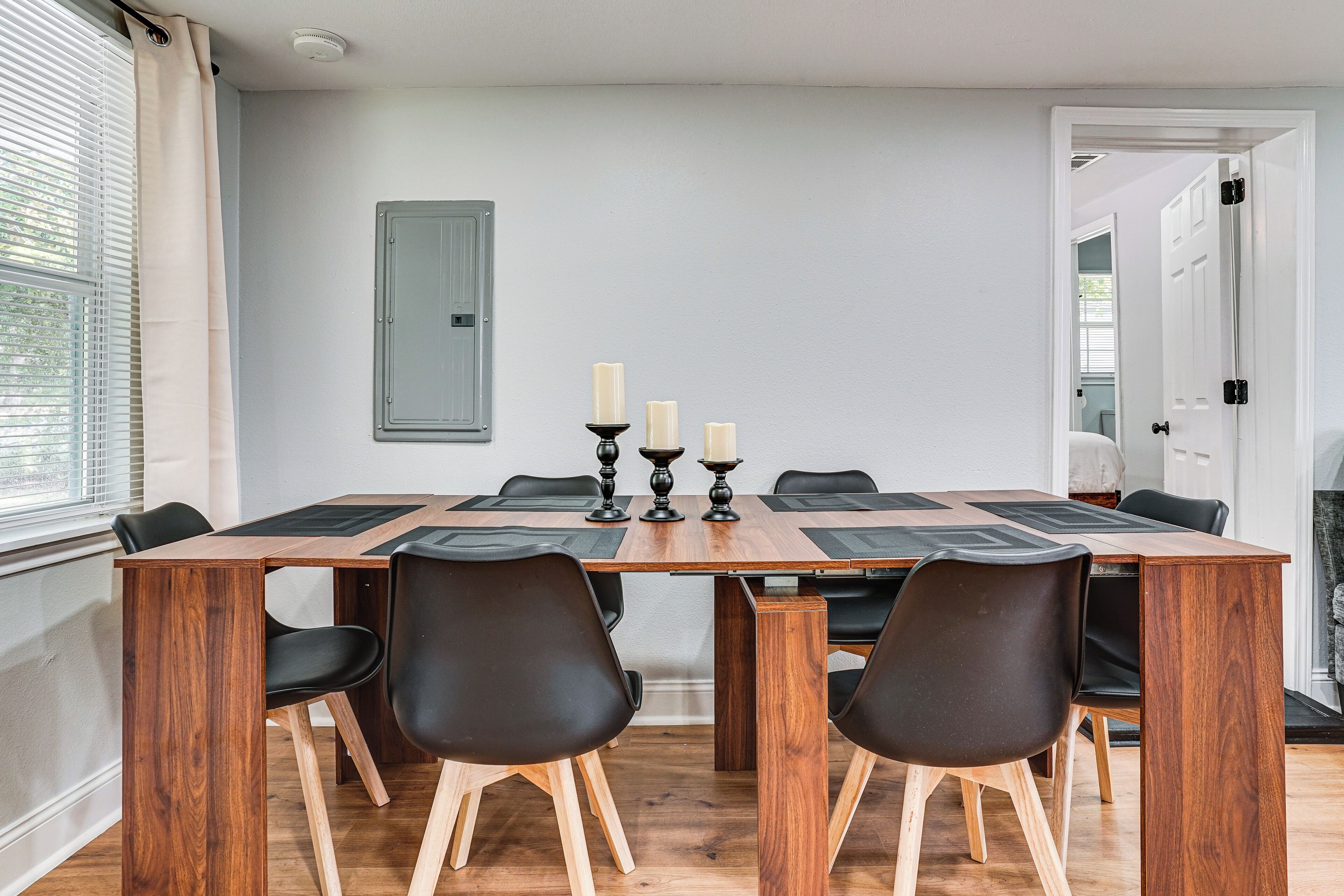 A dining area with a wooden table, black chairs, and candles on the table.