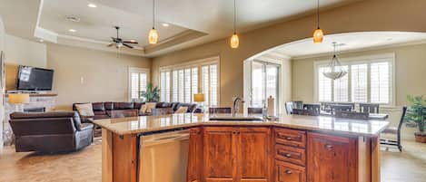A spacious kitchen with a large island, wooden cabinets, and pendant lighting.