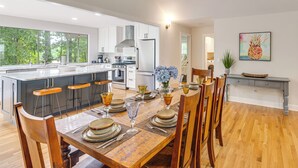 A modern kitchen with a large island, bar stools, and a dining area with a wooden table set for six.