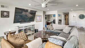 Un salón con televisor, sofá, mesa de centro y ventilador de techo.
