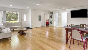 A spacious living area with a sofa, coffee table, dining table with chairs, a TV, and a laundry room. - Deck & Patio! Wurtsboro Haven Near Lakes & Trails (Wurtsboro)