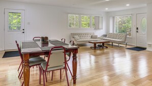 A spacious living area with a dining table, two sofas, and large windows with a view of trees. - Deck & Patio! Wurtsboro Haven Near Lakes & Trails (Wurtsboro)