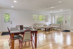 A spacious living area with a dining table, two sofas, and large windows with a view of trees. - Deck & Patio! Wurtsboro Haven Near Lakes & Trails (Wurtsboro)