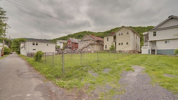 Rua residencial com casas, um quintal cercado e um caminho de cascalho.