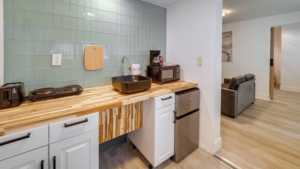 Una cocina moderna con encimera de madera, electrodomésticos de acero inoxidable y salpicadero de azulejos.