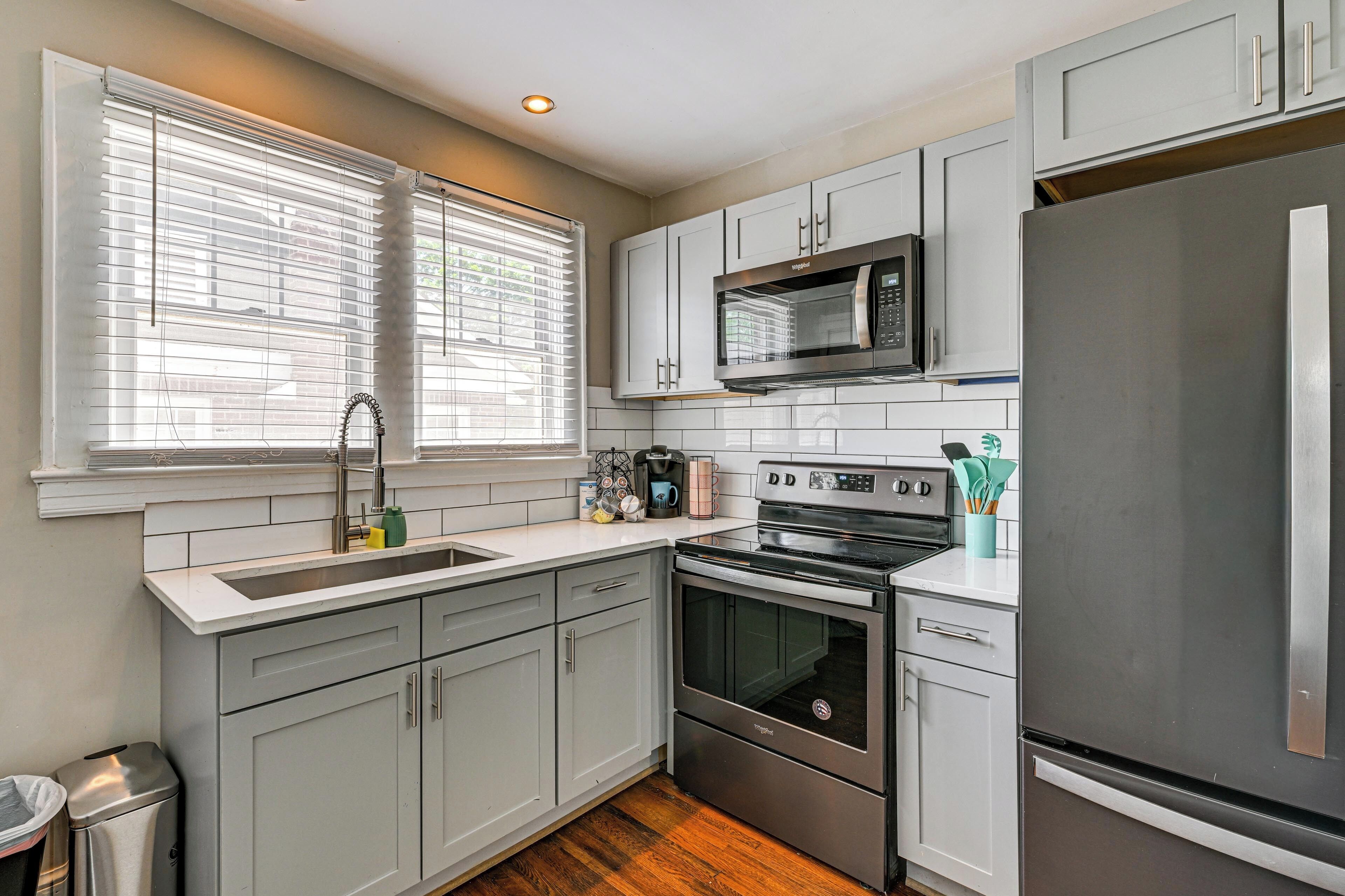 A modern kitchen with grey cabinets, a stainless steel refrigerator, a built-in oven, and a microwave.
