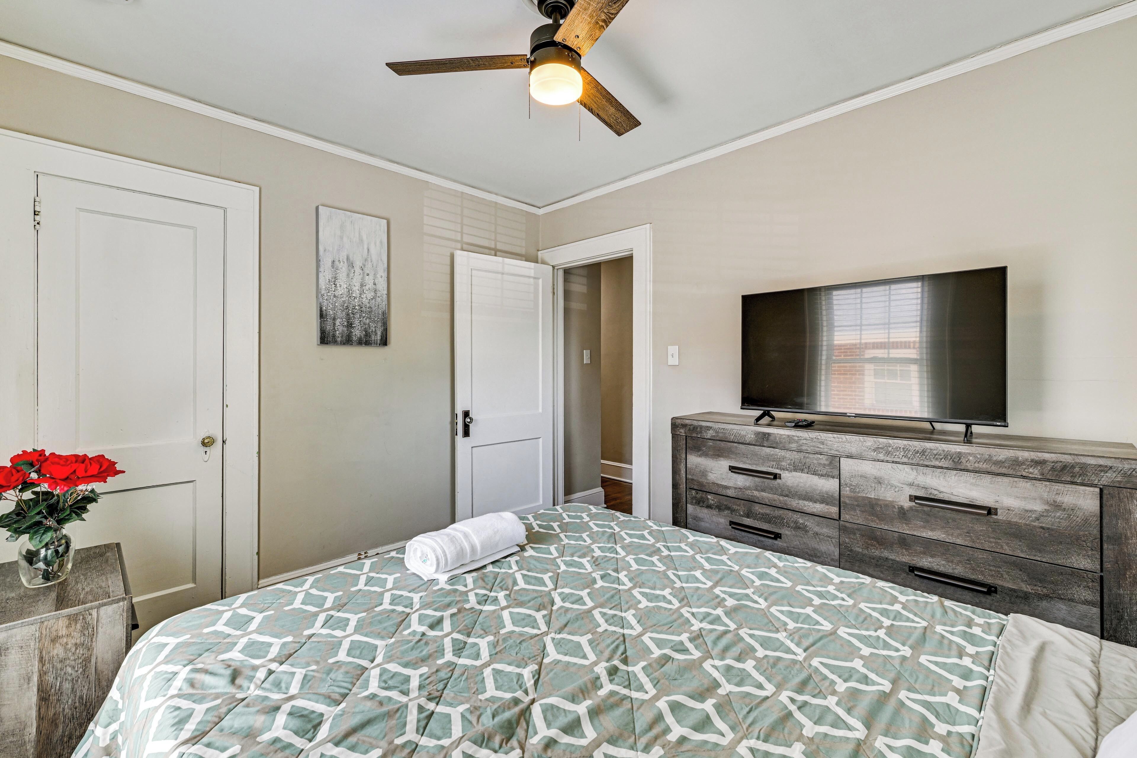 Un dormitorio con cama, cómoda, televisor y ventilador de techo.
