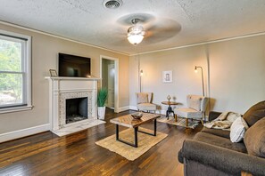 Una sala de estar con chimenea, ventilador de techo y sofá.