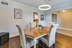 Een eethoek met een houten tafel, vier stoelen en een hanglamp.