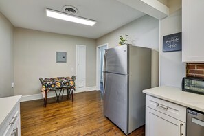 Eine Küche mit einem Edelstahlkühlschrank, einem Holzessttisch und weißen Schränken.