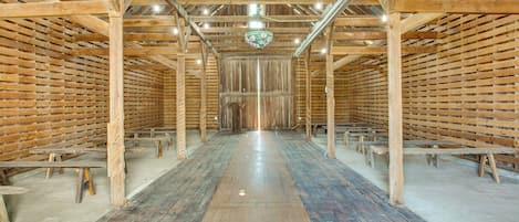 Un gran salón con techo alto, vigas de madera y un pasillo central.
