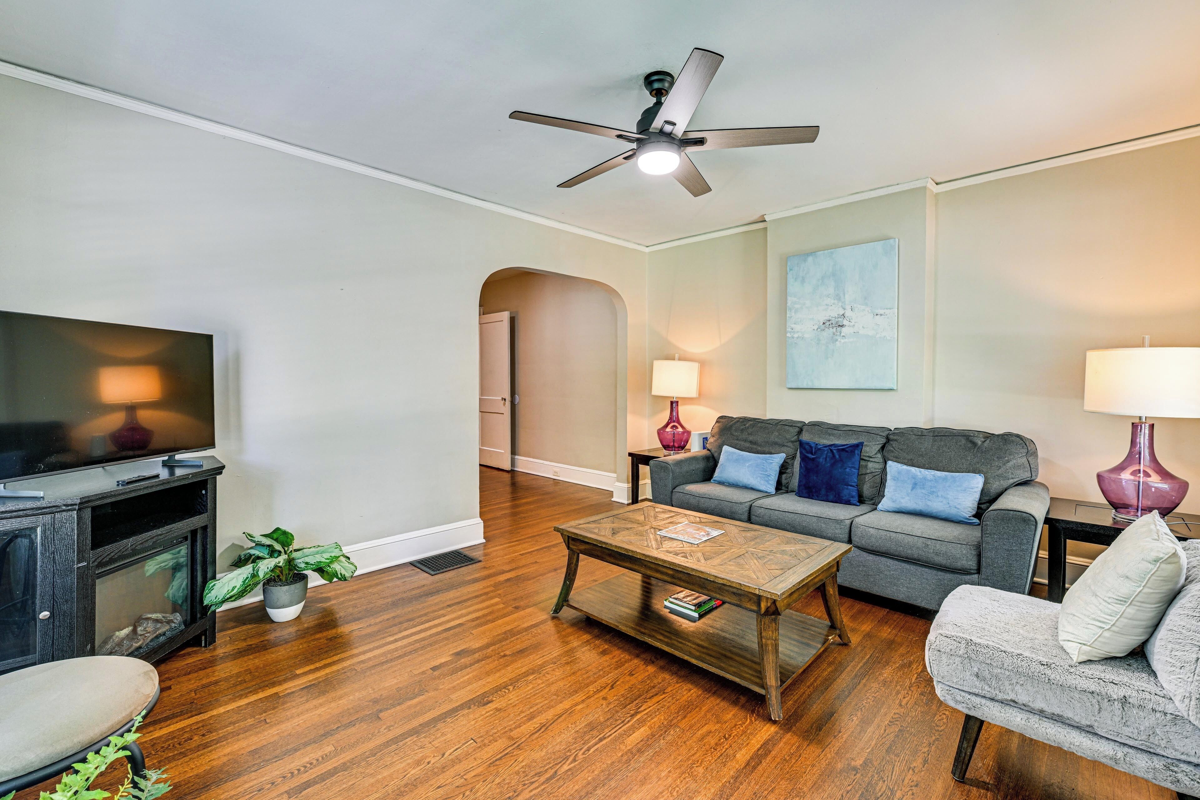 A living room with a TV, sofa, coffee table, and ceiling fan.