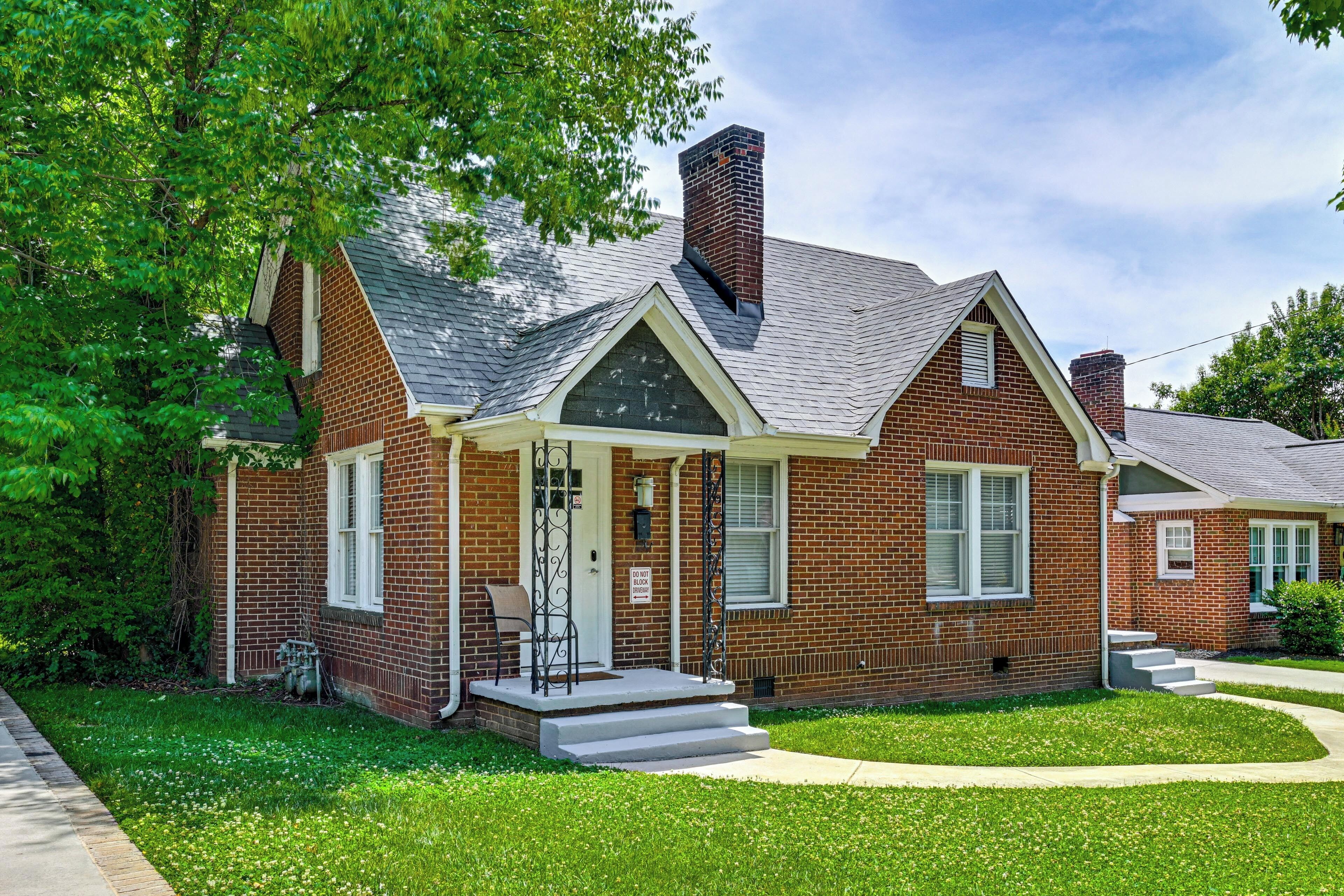A two-story brick house with a front porch, a chimney, and a well-maintained lawn.