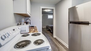 A kitchen with a stove, microwave, and refrigerator, a wooden floor, and a doorway leading to a bedroom. - 3 Mi to Dtwn: Pet-friendly Studio in Huntsville (Huntsville)