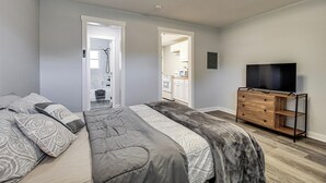 A bedroom with a bed, a dresser, a TV, and a hallway leading to a kitchen. - 3 Mi to Dtwn: Pet-friendly Studio in Huntsville (Huntsville)