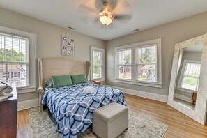 Ein Schlafzimmer mit einem großen Bett, einem Deckenventilator und Blick ins Freie durch Fenster.