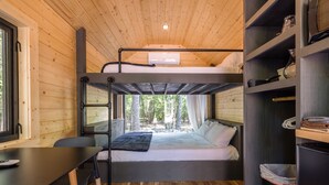A bunk bed room with a desk, a window with a view of trees, and a built-in shelf with kitchen items. - Glamping at Four Fillies Lodge-The Maid Marian (Peterstown)