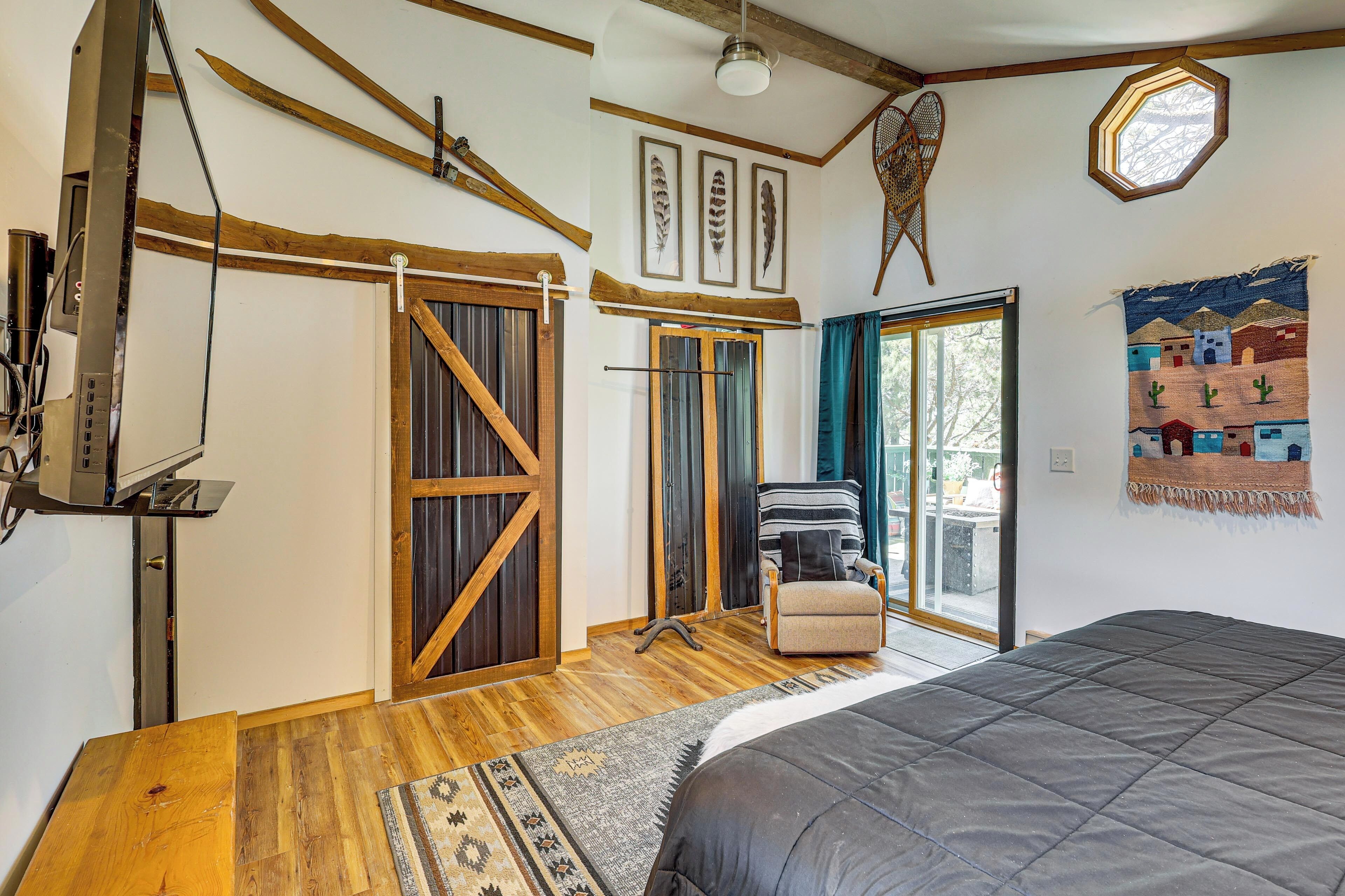 A bedroom with a bed, wooden flooring, a sliding door, a chair, and a window.