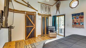 A bedroom with a bed, wooden flooring, a sliding door, a chair, and a window.