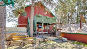 Un chalet rustique doté d’une véranda, d’un escalier en bois et d’un espace salon extérieur.