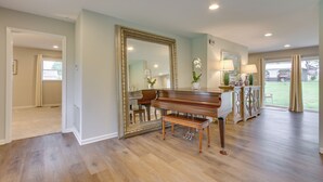 Um quarto amplo com um piano de cauda, um espelho grande e vista para o exterior.