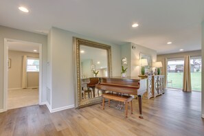A spacious room with hardwood flooring, a grand piano, a large mirror, and a view of the outdoors. - Angler-friendly Retreat Near Tennessee River (Florence)