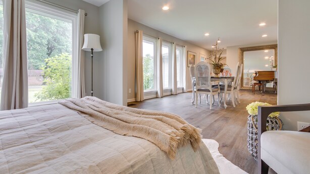 Quarto com cama grande, área de refeições e vista para o verde.