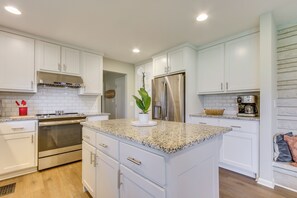 A modern kitchen with white cabinets, stainless steel appliances, granite countertops, and a central island. - Angler-friendly Retreat Near Tennessee River (Florence)