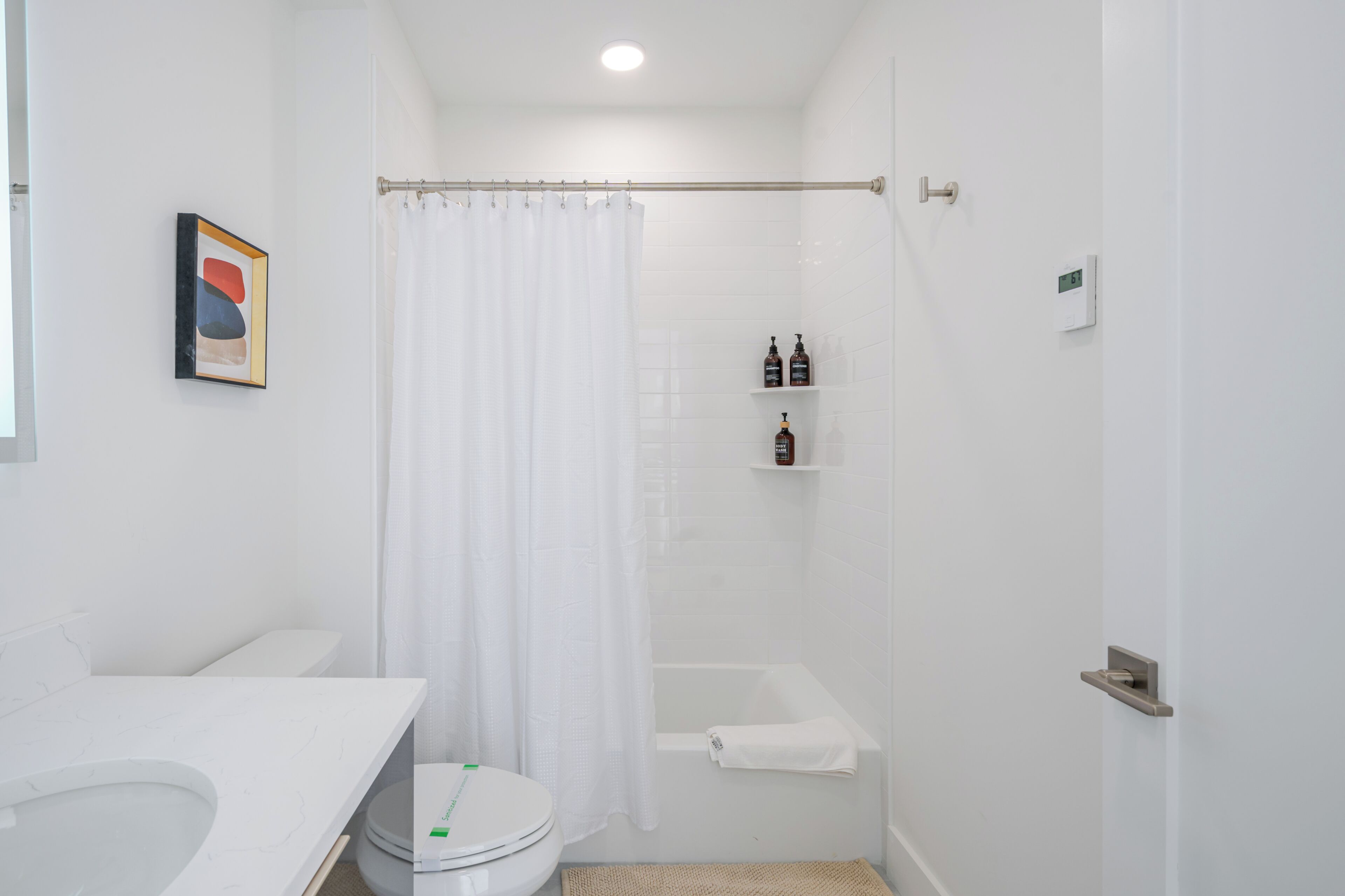 Een moderne badkamer met toilet, douche en bad.