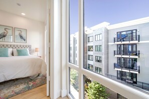 Ein Schlafzimmer mit großem Fenster, einem Bett und Bildern an der Wand.
