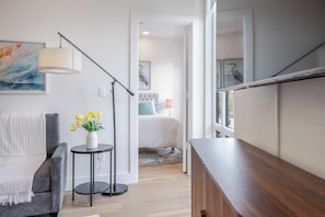 Ein modernes Schlafzimmer mit Bett, Nachttisch, Lampe und Kunstwerk.