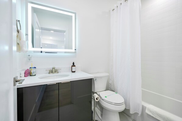 A modern bathroom with a white sink, mirror, and toilet.