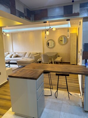 Una cocina moderna con encimera de madera, muebles de color blanco y una zona de comedor con mesa y sillas.