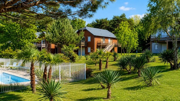 Zona residencial con piscina, patio cercado y casas con balcones.