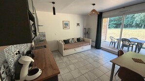Un espacio habitable compacto con kitchenette, sofá cama, zona de comedor y vistas al exterior.