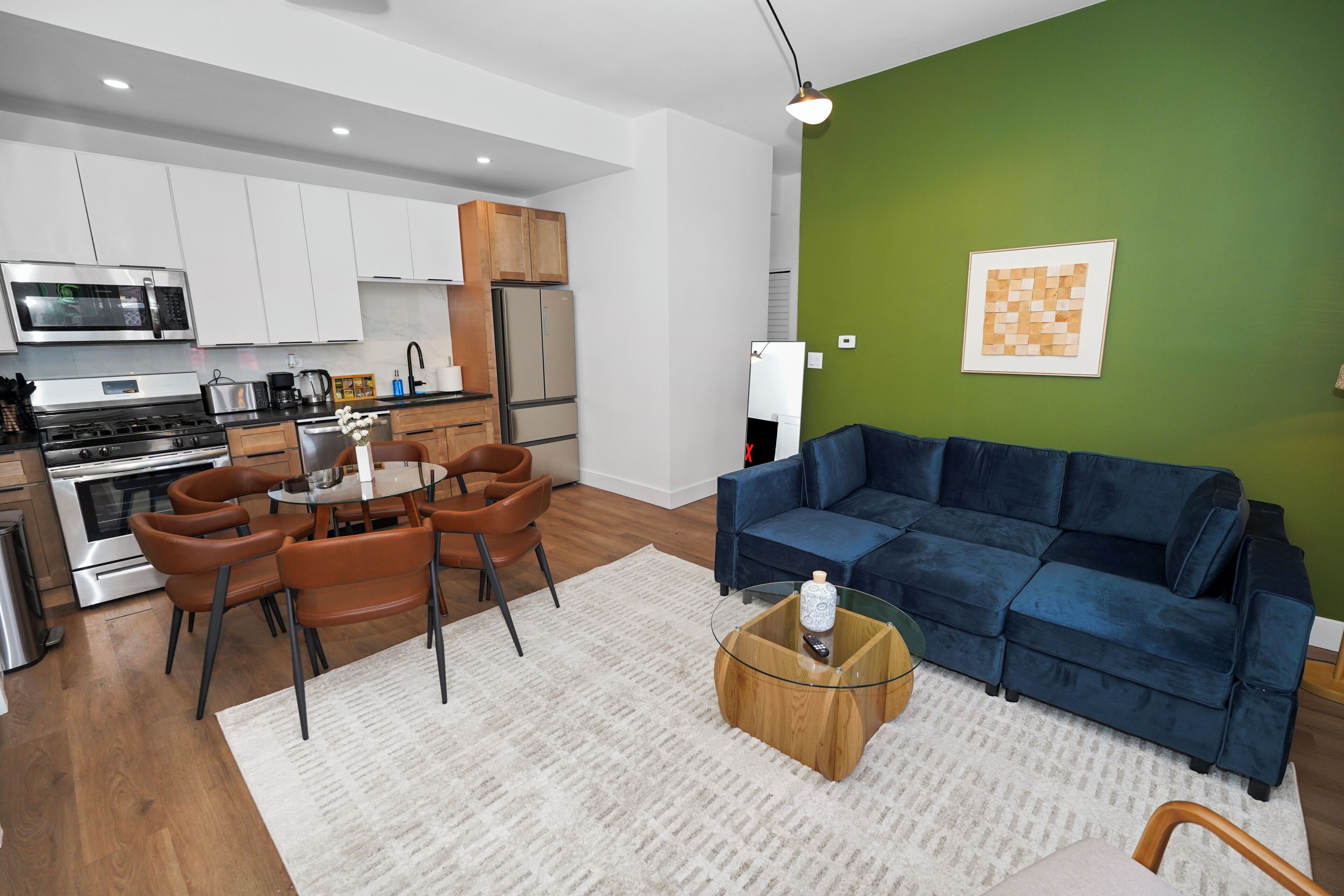 A modern kitchen with white cabinets, a stainless steel microwave, and a built-in oven.