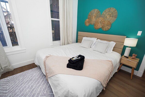 A bedroom with a bed, a bedside table, a lamp, and a wall decoration.