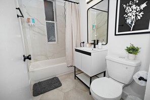 Une salle de bain équipée d’une baignoire, de toilettes, d’un lavabo et d’un rideau de douche.