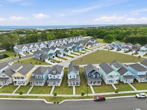 A residential area with multiple two-story houses, a central green space, and a road with vehicles.